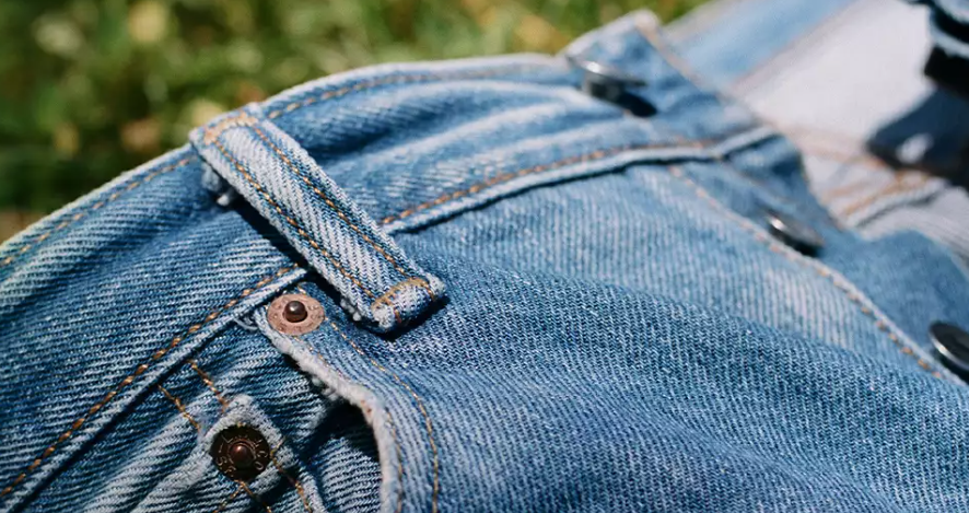 Eine blaue Jeanshose vor einem grünen Hintergrund